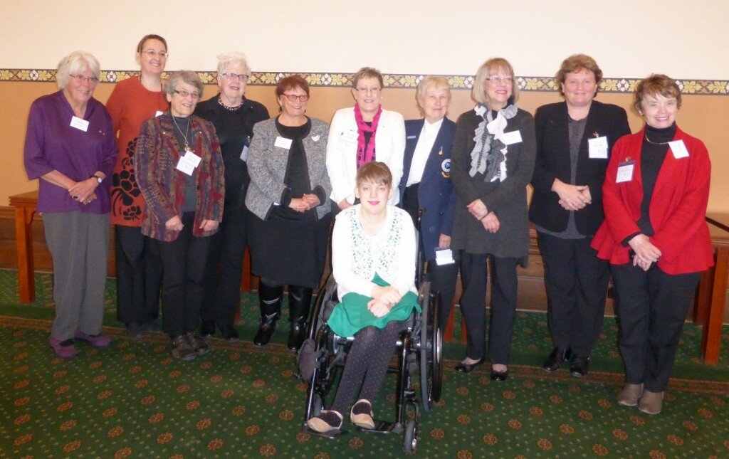 This is a photograph of all of the women that attended the morning tea. From left to right - Valmai Hankel, Bogda Koczwara, Monica Oliphant, Rosemary Crowley, Jane Lemon, Christine Russell, Yvonne Hill, Lesley Hawkins, Tracey Murphy, Margaret Springgay. Kelly Vincent is sitting in her manual wheelchair in front of the group. They are all smiling and looking in the direction of the camera.